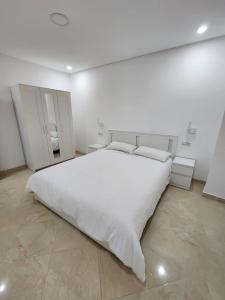 1 dormitorio blanco con 1 cama grande con sábanas blancas en Appartements climatisés JANYA HOLIDAYS, en Alhucemas