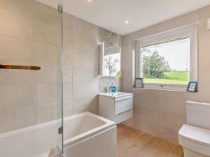 a bathroom with a tub and a toilet and a window at 3 Bed in Alnwick 93171 in Edlingham +18 photos