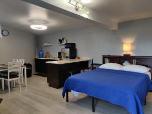 a bedroom with a blue bed and a desk and a kitchen at LaBellevue Benjamin's Holiday Rental Home﻿ in Crosbies