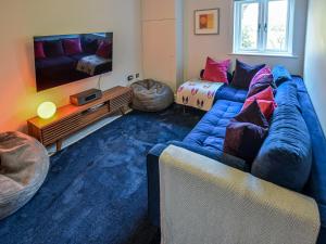 un salon avec un canapé bleu et une télévision dans l'établissement 3 Bed in Tenterden 83843, à Saint Michaels