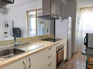 cocina con fregadero y nevera en Apartamento Mariscal 4, 13 con piscina y vistas al mar, en Benidorm