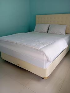 een bed met witte lakens en kussens in een kamer bij RIUNG LALONG TERONG Guest House in Riung