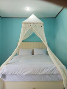 RiungにあるRIUNG LALONG TERONG Guest Houseのベッドルーム(天蓋付き白いベッド1台付)