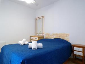 Un dormitorio con una cama azul con toallas. en Apartamento Mariscal 4, 13 con piscina y vistas al mar, en Benidorm