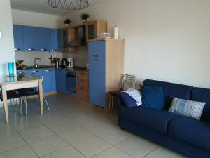 a living room with a blue couch and a kitchen at Algajola in Algajola