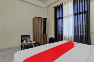 een slaapkamer met een bed, een bureau en een stoel bij OYO Flagship Hotel New A V Hospitality in Chinhat
