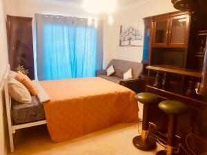 a bedroom with a bed and a couch and blue curtains at Plaza near Forum Madeira in Funchal