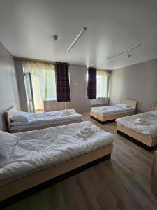 3 Betten in einem Zimmer mit Holzböden und Fenstern in der Unterkunft Біля Замку in Lwiw