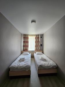 2 Betten in einem kleinen Zimmer mit Fenster in der Unterkunft Біля Замку in Lwiw