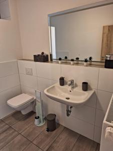 a bathroom with a sink and a toilet and a mirror at Ferienwohnung Diemel in Bad Karlshafen