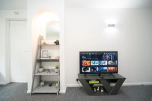 ein Wohnzimmer mit einem TV und einem Regal in der Unterkunft Pass the Keys Spacious Wembley Apartment with Free Parking in London