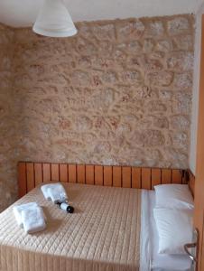 a bed with two towels and a brick wall at Niko's Stone Guest House in Plitra