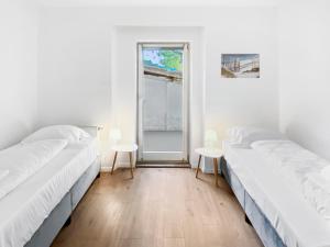 twee bedden in een kamer met twee tafels en een raam bij feworld living - Deutsch Wagram bei Wien in Deutsch-Wagram