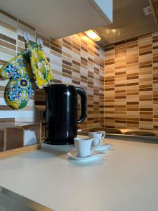 una cafetera negra y dos tazas en un mostrador en Casa Melany en Taormina