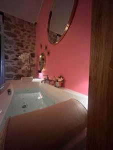 a bath tub in a bathroom with a pink wall at Suite Love Room Les Secrets d'Eden Rose- escapade romantique à 2 in Limoges