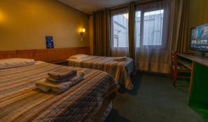 um quarto de hotel com duas camas e uma televisão de ecrã plano em Hotel Condor de Plata em Punta Arenas