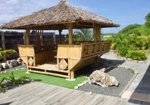 a wooden gazebo with a straw roof at Nakolodge -3 chambres - piscine et jardin privatifs in Sainte-Anne