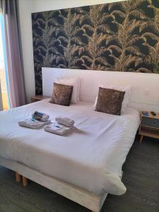 a large white bed with two towels on it at Hôtel de la Mer in Valras-Plage