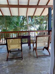 a patio with two chairs and a table on a porch at Curry Bowl Restaurant & Turtles Rest in Hikkaduwa