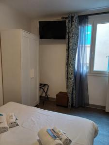 sypialnia z łóżkiem i oknem z telewizorem w obiekcie Hôtel de la Mer w mieście Valras-Plage