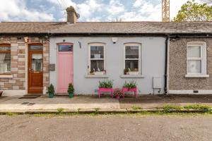 ein weißes Haus mit einer rosa Tür und zwei rosa Bänken in der Unterkunft Cozy room in Stoneybatter, Dublin in Dublin