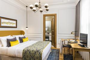 イスタンブールにあるNevv Bosphorus Hotel & Suitesのベッドと机とテレビがあるホテルの部屋