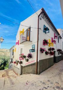 ein weißes Gebäude mit Blumen an den Fenstern in der Unterkunft Calle Villa Baja Castril in Castril