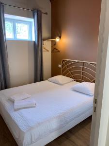 a bedroom with a bed with white sheets and a window at Hôtel Des Docks in Digoin