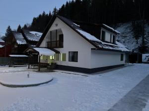a white house with snow on the ground at Vila Izvorul Muntelui in Bicaz +11 photos