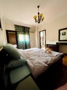 a bedroom with a large bed and a chandelier at 3Bedroom next to Downtown Mall New Cairo in Cairo