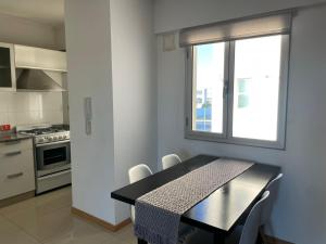 uma pequena cozinha com uma mesa e uma janela em Departamentos Leloir em Neuquén