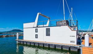 ein kleines weißes Gebäude auf einer Anlegestelle im Wasser in der Unterkunft Fenyves Yacht Club Superior in Balatonfenyves