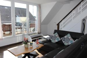 a living room with a black couch and a table at Haus Deutsche Bucht in Borkum
