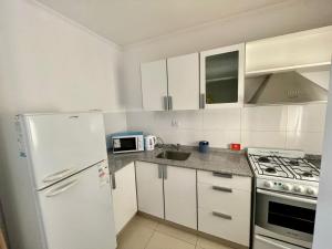 eine Küche mit weißen Schränken und einem weißen Kühlschrank in der Unterkunft Departamentos Leloir in Neuquén