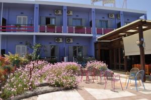 a blue building with chairs and flowers in front of it at Okeania Seafront Rooms in Kamena Vourla in Kamena Vourla