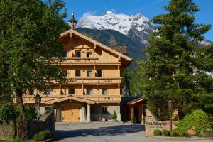 a large wooden building with a snow covered mountain at Gut Stiluppe - Good Life Hotel in Mayrhofen