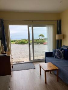 ウォーターフォードにあるBeautiful one bed apartment with stunning sea viewのリビングルーム(青いソファ、ガラスの引き戸付)