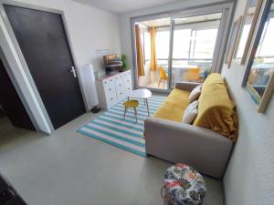 a living room with a couch with a yellow blanket at Appartement Plage des Arts in Saint-Cyprien