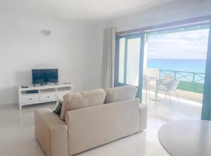 un soggiorno con divano bianco e TV di Blancazul Avenida a Playa Blanca