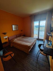a bedroom with a bed and a large window at Hotel Panoramico lago d'Orta in Madonna del Sasso