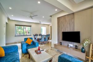 uma sala de estar com cadeiras azuis e uma televisão em Premium 2BHK Apartment with pool at Candolim Beach em Candolim