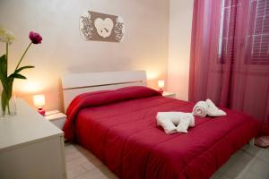 1 dormitorio con 1 cama roja y 2 toallas en Casa Vacanze La Coccinella, en Trapani