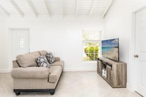 a living room with a couch and a flat screen tv at NEW Tropical Bottle Creek Stay Beach 5 min Drive in NCA