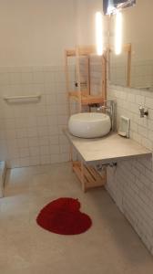 baño con lavabo y alfombra roja en B&B il riccio, en Paspardo