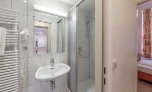 uma casa de banho branca com um lavatório e um chuveiro em Hotel Terminus em Viena