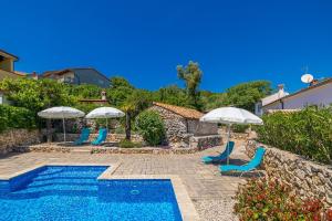 a swimming pool with two chairs and umbrellas at Villa Neva - Cizici, Krk in Čižići