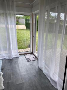 Una habitación vacía con cortinas blancas y una puerta corrediza de vidrio. en Bungalow dans le jardin, en Saint-Étienne
