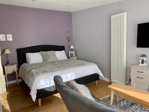 a bedroom with a bed and a chair and a television at Cosy Little Barn near Bath in Rode