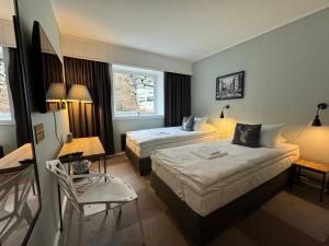 una camera d'albergo con due letti e una sedia di Arctic Hotel Nordkapp a Honningsvåg