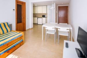een woonkamer met een tafel, een bank en een bureau bij Apartments Sorrabona in Pineda de Mar